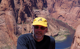 man wearing hat and sunglasses with a canyon in the background