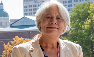 woman standing on a balcony with the Indianapolis skyline behind her