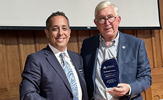 two men standing together, once of whom has been presented with an award
