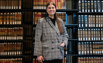 woman standing in front of a stack of law books in a law library